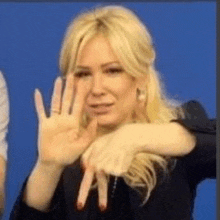 a woman with blonde hair is making a stop sign with her hands .