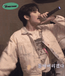 a young man is singing into a microphone with a green sticker that says the boynextdoor