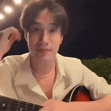 a young man is playing a guitar in a dark room .