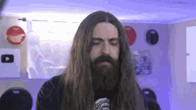 a man with long hair and a beard is in a room with a youtube logo on the wall .
