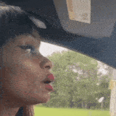 a woman wearing red lipstick is sitting in a car with a sun visor on it .