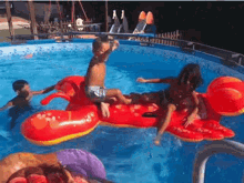 a group of children are playing in a swimming pool with a red lobster float