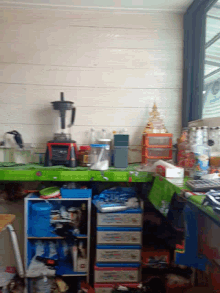 a kitchen with a blender a microwave and a stack of boxes that say ' coca cola '