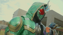 a green superhero with a red eye and a hood