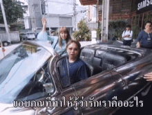 a man and a woman are sitting in a car in front of a sign that says samsl