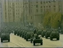 a parade of military vehicles is going down a city street