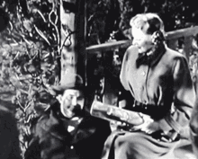 a black and white photo of a man and woman sitting on a bench