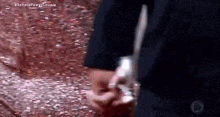 a close up of a person 's hand holding a piece of paper on the ground .