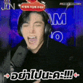 a man wearing headphones is screaming into a microphone with the words t98 strong above him