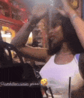 a woman wearing a white tank top with a black purse and a smiley face on the bottom