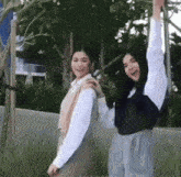 two women are standing next to each other with their arms in the air and smiling .