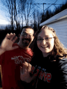 a man and a woman are posing for a picture and the woman is wearing a wilson t-shirt