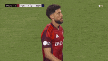 a soccer player wearing a red jersey with bmo on the front