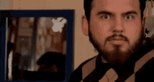 a man with a beard is standing in front of a mirror and making a funny face .