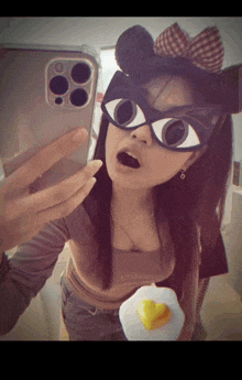 a woman is taking a selfie with her phone while wearing a mask that looks like a cat 's eye