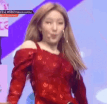 a woman in a red off the shoulder top is dancing on stage