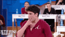 a man in a maroon shirt with the letter a on it
