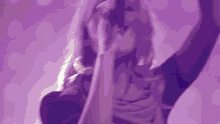 a close up of a woman singing into a microphone on a purple background .