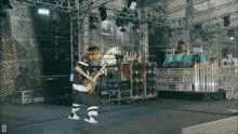 a man is playing a guitar on a stage with the letter d below him