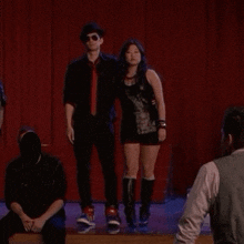 a group of people standing on a stage with a red curtain in the background