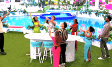 a group of people are standing around a table in front of a swimming pool