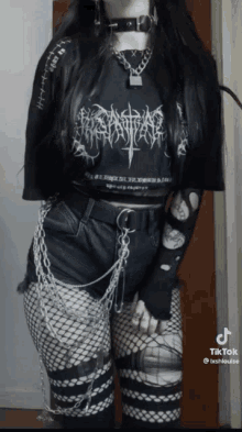 a girl wearing a black shirt that says ' apocalypse ' on it is standing in front of a door