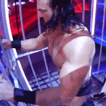 a wrestler is kneeling down in a cage with a rope around his waist