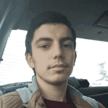 a young man sitting in a car taking a picture of himself