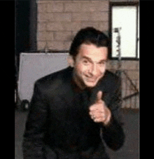 a man in a suit is giving a thumbs up sign .