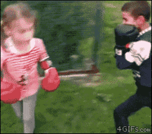 a girl wearing red boxing gloves stands next to a boy wearing black boxing gloves ..