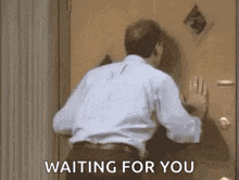 a man is standing in front of a door waiting for someone to come in .