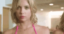 a woman in a pink bikini is standing in front of a mirror looking at herself .