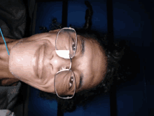 a man with curly hair wearing glasses looks down at the camera