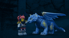 a girl standing next to a blue toy dragon with yellow wings