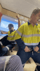 a man in a yellow safety vest is standing in front of another man