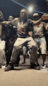 a group of men are dancing together on the sidewalk .