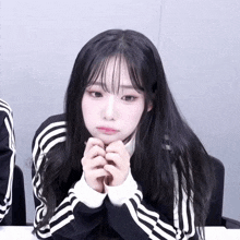 a girl with long black hair is wearing a black and white adidas jacket