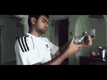 a man in an adidas shirt is opening a bottle of water