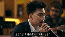 a man wearing glasses is singing into a microphone with a caption in another language