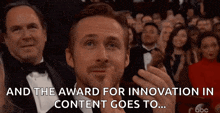 a man in a tuxedo is giving a thumbs up in front of a crowd at an awards ceremony .