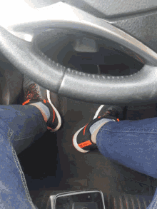 a person wearing a pair of nike shoes is sitting in the driver 's seat