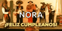 a group of mariachi players are standing on a stage and singing .