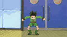 a boy in a green jacket and green shorts is standing in front of a blue door