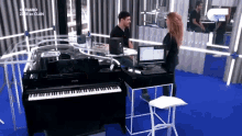 a man and a woman are standing in front of a piano in a room that says diario on the wall