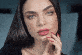 a close up of a woman 's face with red nails and pink lips