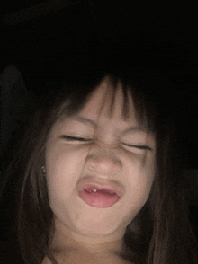 a little girl with her eyes closed making a funny face