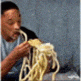a man is eating noodles with a fork and spoon .