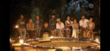 a group of people sitting in a circle with a fire in the middle and the letters n on the bottom right