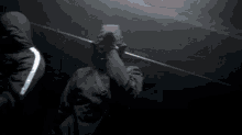 a man wearing a gas mask and a black jacket stands in the dark