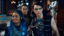 a woman with blue hair is standing next to a man and a boy